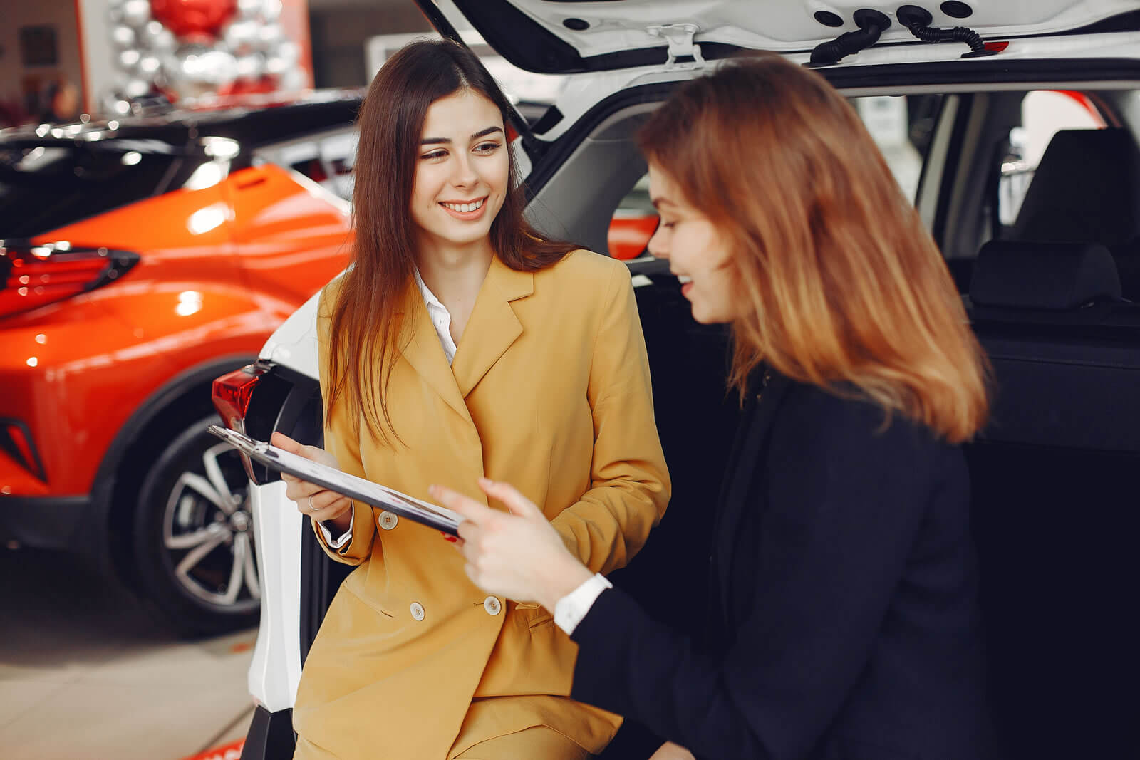 A car dealer speaking to a customer in front of cars